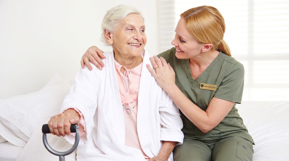 A caregiver sitting with a client at the bedside