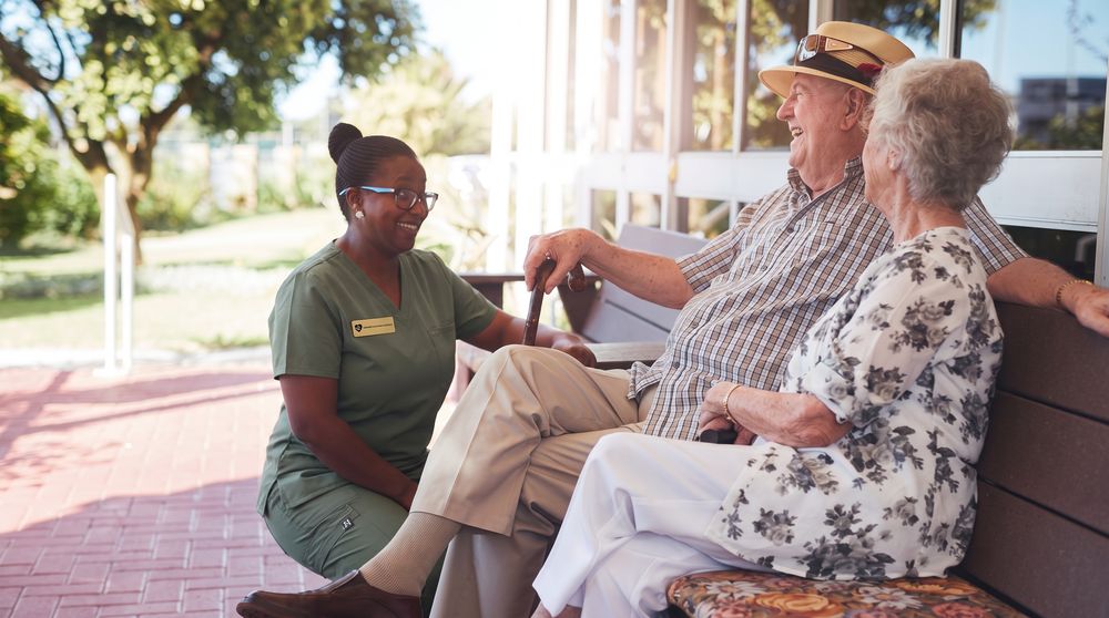 A caregiver seated with an older couple outdoors