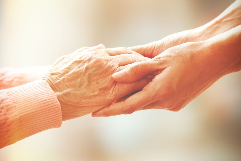 A younger hand resting gently over an older hand