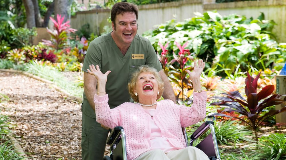 A caregiver and client laughing together in a garden